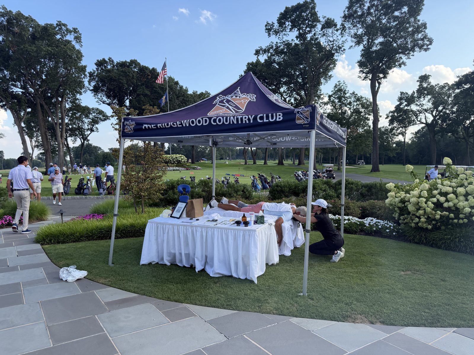 The Kinetic tent and table set up at the Ridgewood Country Club, golfers and the course behind.